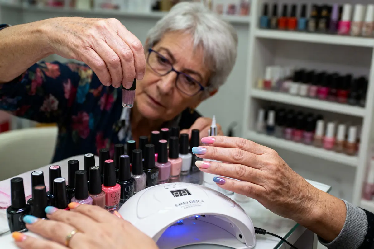 pexels-michal-pech-213601-757318 (1) Une femme choisissant du vernis à ongles parmi une collection, mains manucurées devant une lampe UV.