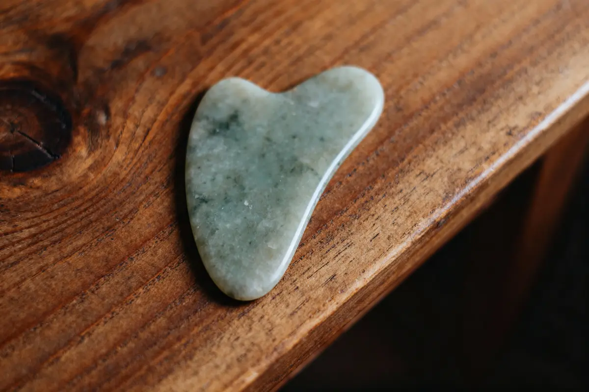 Pierre de jade en forme de cœur sur une table en bois.