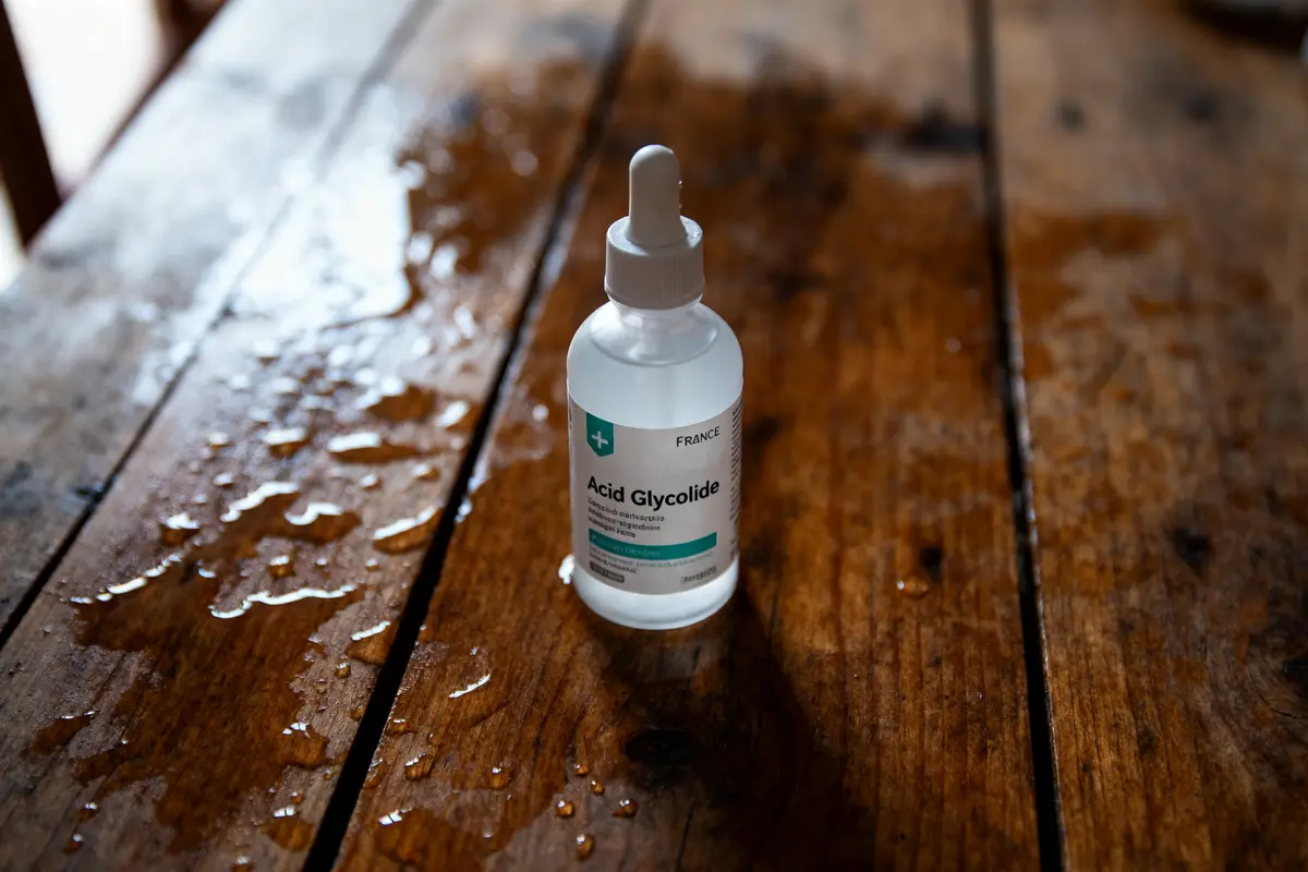 pexels-michal-pech-213601-757318 (1) Bouteille d'acide glycolique avec pipette sur table en bois mouillée, lumière naturelle.